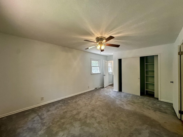 unfurnished bedroom featuring a textured ceiling, dark colored carpet, and baseboards