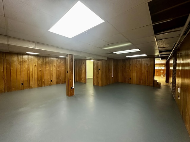 finished basement with a paneled ceiling and wooden walls