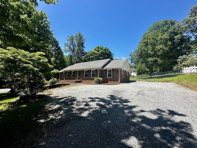 ranch-style home featuring fence, brick siding, and driveway
