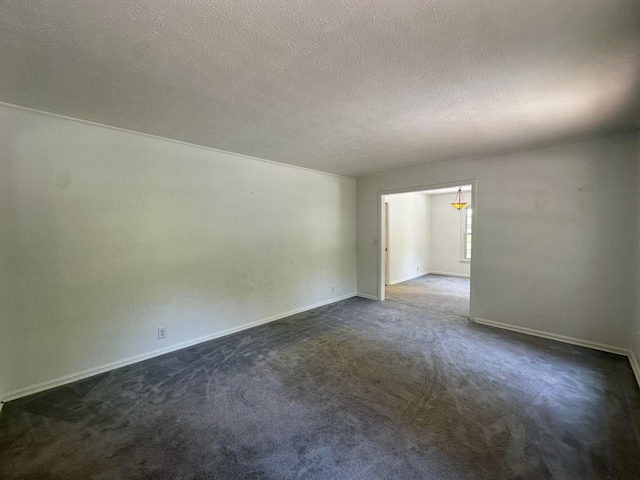 unfurnished room with baseboards, dark carpet, and a textured ceiling