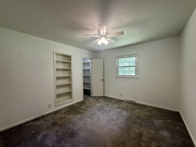 unfurnished bedroom with a ceiling fan, a textured ceiling, baseboards, dark colored carpet, and visible vents