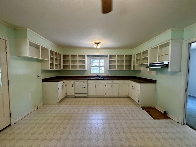 kitchen featuring open shelves, dishwasher, dark countertops, and a sink