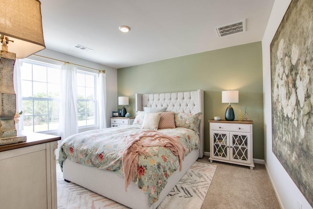bedroom featuring visible vents, baseboards, and light carpet