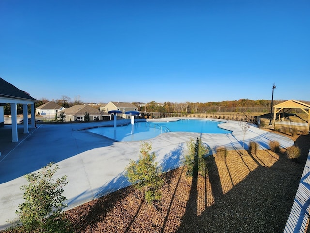 community pool with fence, a gazebo, and a patio area