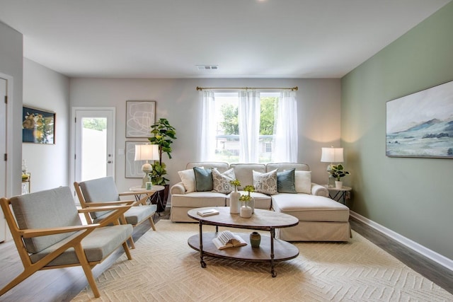 living area featuring light wood-style flooring, baseboards, and visible vents