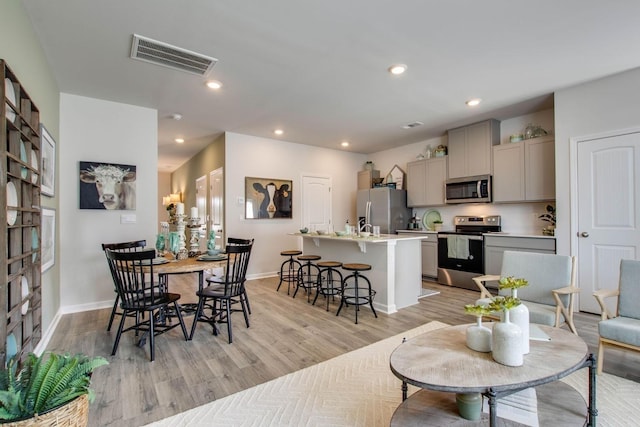 dining space with baseboards, light wood-type flooring, visible vents, and recessed lighting