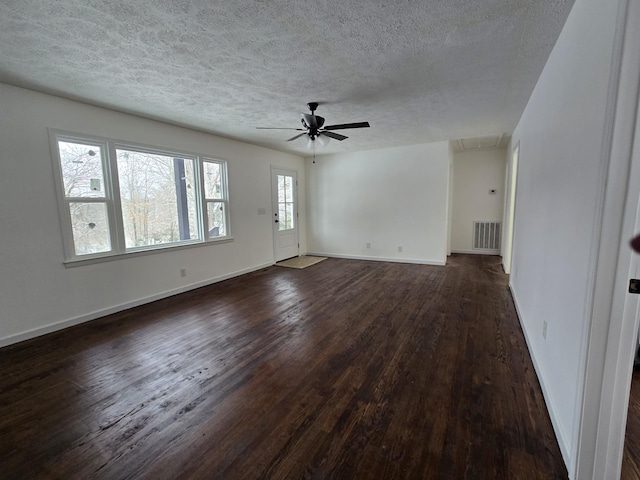 unfurnished living room with a textured ceiling, attic access, dark wood-style floors, and visible vents