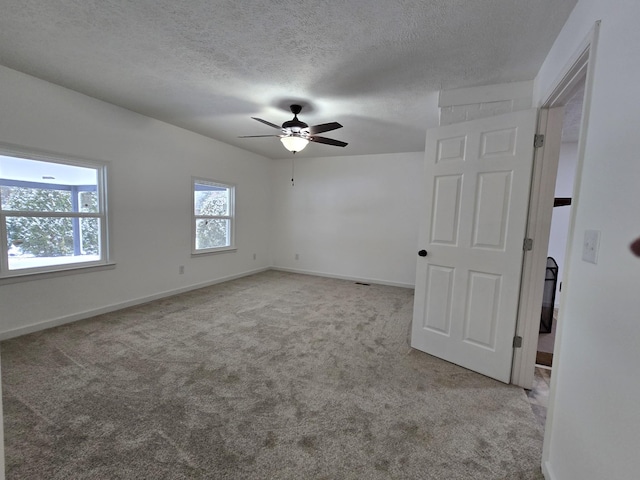 carpeted empty room featuring a textured ceiling, baseboards, and ceiling fan