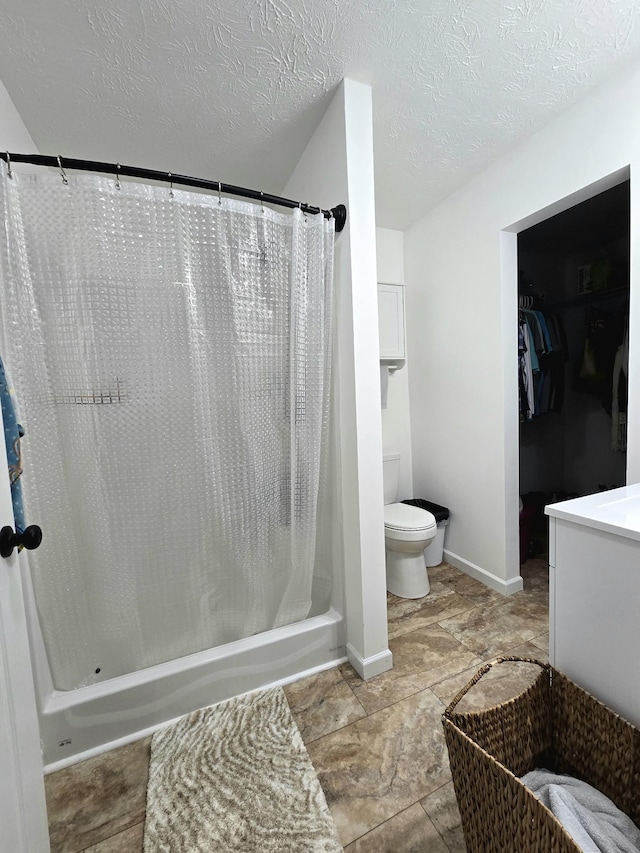 bathroom featuring vanity, toilet, a textured ceiling, and baseboards