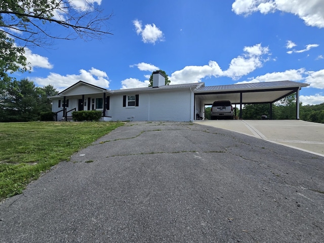 ranch-style house with a chimney, a front yard, driveway, and a carport
