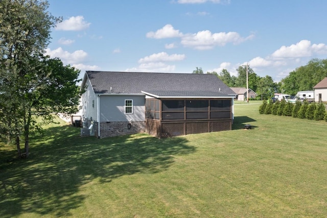 rear view of house featuring a sunroom, a shingled roof, and a lawn