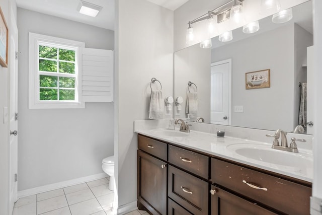 bathroom featuring a sink, double vanity, toilet, and baseboards