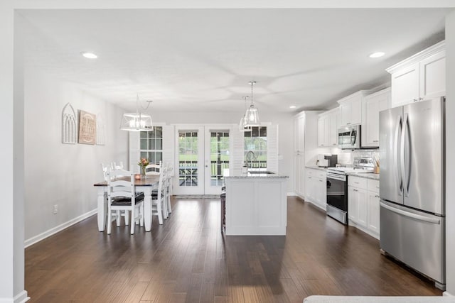 kitchen featuring baseboards, stainless steel appliances, white cabinets, and a sink