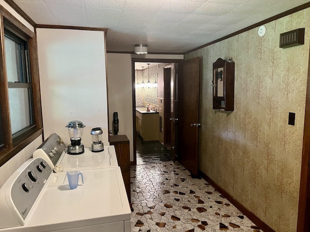 hallway featuring washer and dryer, stone finish floor, and ornamental molding