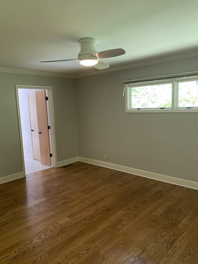 spare room featuring ceiling fan, ornamental molding, baseboards, and dark wood-style floors
