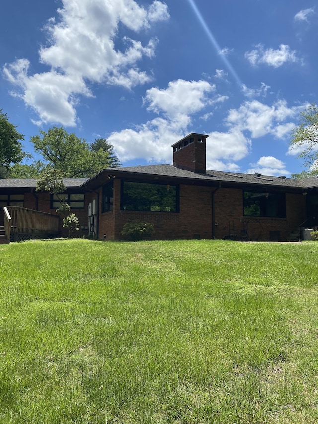 rear view of property featuring a chimney and brick siding