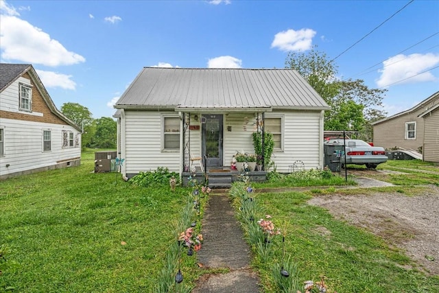 bungalow-style house with covered porch, metal roof, a front lawn, and central AC unit