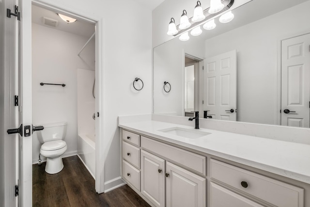 bathroom featuring toilet, wood finished floors, baseboards, vanity, and shower / bathtub combination