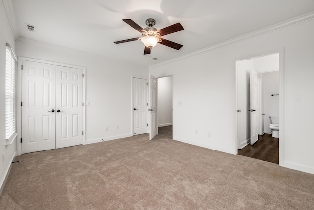 unfurnished bedroom featuring baseboards, carpet flooring, crown molding, and two closets