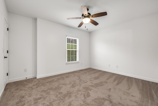 spare room featuring baseboards, ceiling fan, and carpet