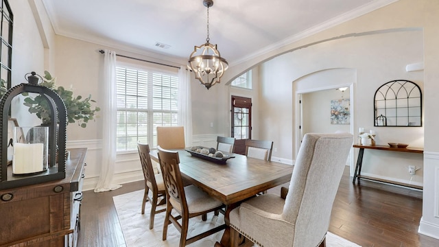 dining room featuring arched walkways, a wealth of natural light, a notable chandelier, and wood-type flooring