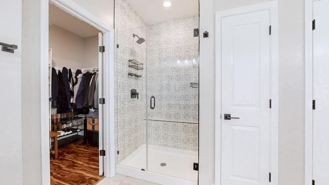 full bath with a stall shower, wood finished floors, recessed lighting, and a walk in closet