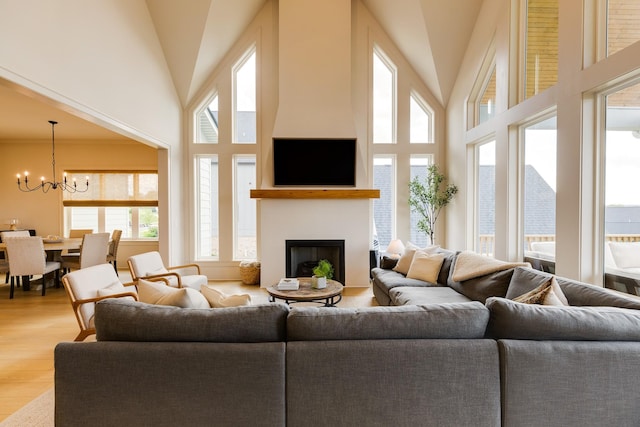living room featuring a fireplace, a chandelier, plenty of natural light, and wood finished floors