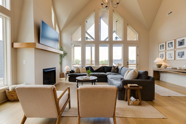 living area featuring plenty of natural light, visible vents, a fireplace, and high vaulted ceiling