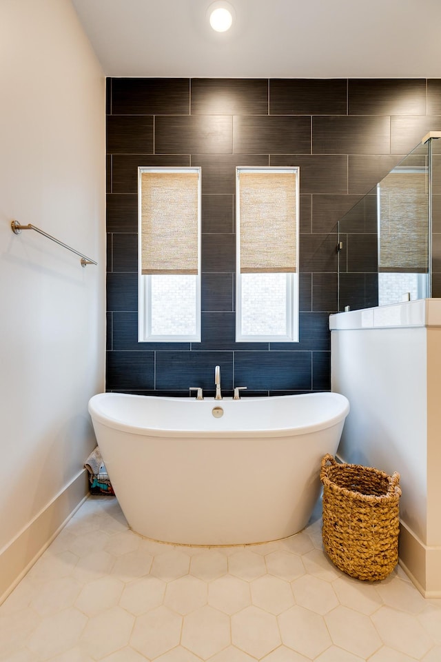 full bath featuring walk in shower, a soaking tub, and baseboards
