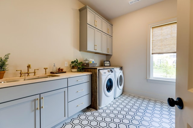 washroom featuring washer and clothes dryer, cabinet space, a sink, and visible vents