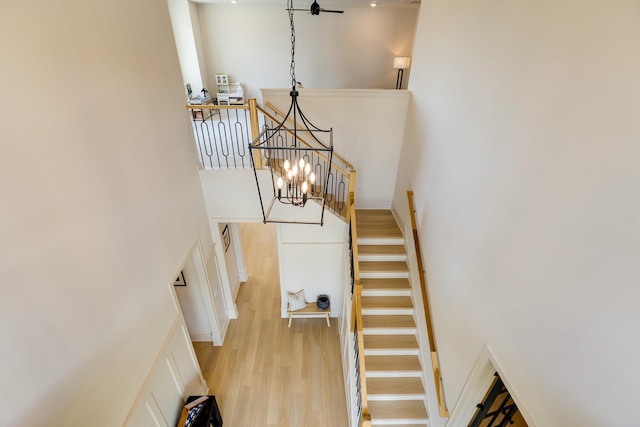 stairs with a notable chandelier, a high ceiling, and wood finished floors