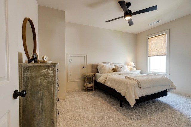 bedroom featuring light colored carpet, visible vents, baseboards, and a ceiling fan
