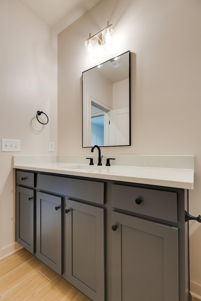 bathroom featuring baseboards, visible vents, wood finished floors, and vanity