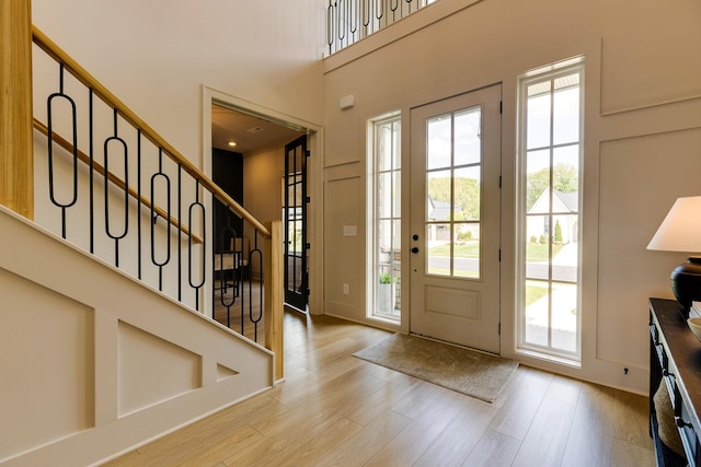 entryway featuring light wood finished floors, stairway, and a towering ceiling