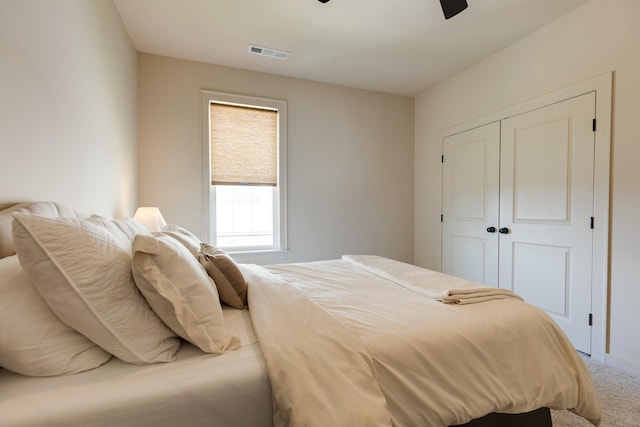 carpeted bedroom featuring a ceiling fan, a closet, and visible vents