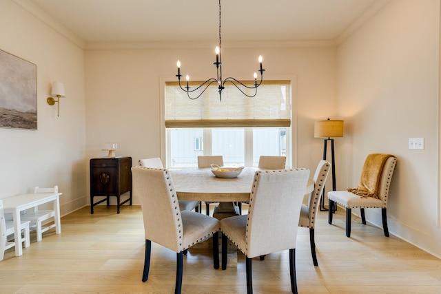 dining space featuring baseboards, ornamental molding, light wood finished floors, and a chandelier