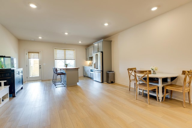 kitchen featuring light wood-type flooring, high end fridge, a kitchen bar, light countertops, and gray cabinetry