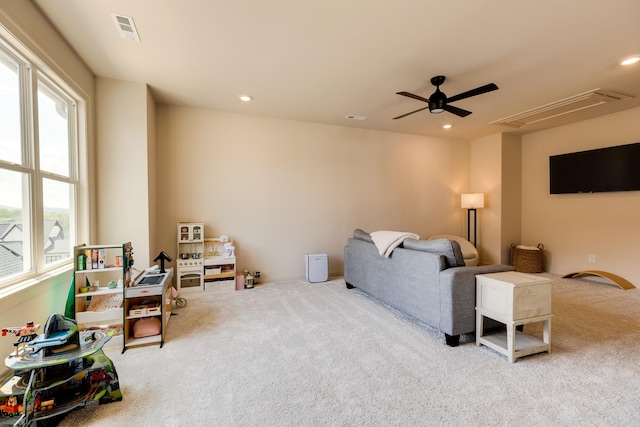 living room with carpet flooring, attic access, visible vents, and ceiling fan