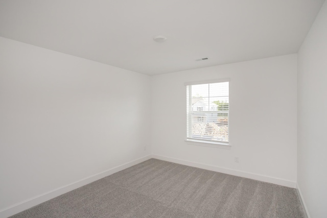 empty room featuring baseboards, visible vents, and light colored carpet