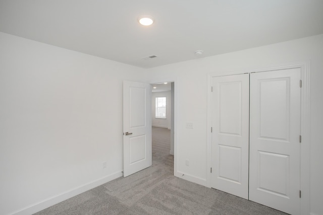 unfurnished bedroom featuring light carpet, baseboards, a closet, and visible vents