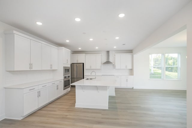 kitchen with wall chimney range hood, appliances with stainless steel finishes, baseboards, and a sink