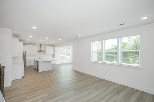 unfurnished living room with recessed lighting, baseboards, visible vents, a sink, and light wood-style floors