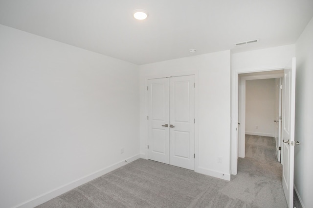 unfurnished bedroom with a closet, light carpet, baseboards, and visible vents