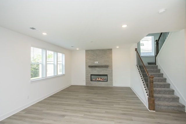unfurnished living room featuring stairway, a wealth of natural light, and light wood-type flooring