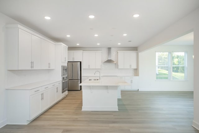 kitchen with a sink, stainless steel appliances, recessed lighting, and wall chimney exhaust hood