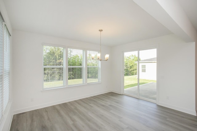 unfurnished dining area featuring an inviting chandelier, baseboards, and wood finished floors