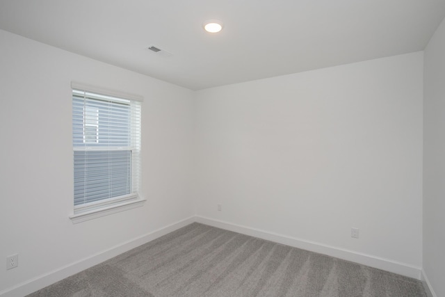 carpeted empty room featuring baseboards and visible vents