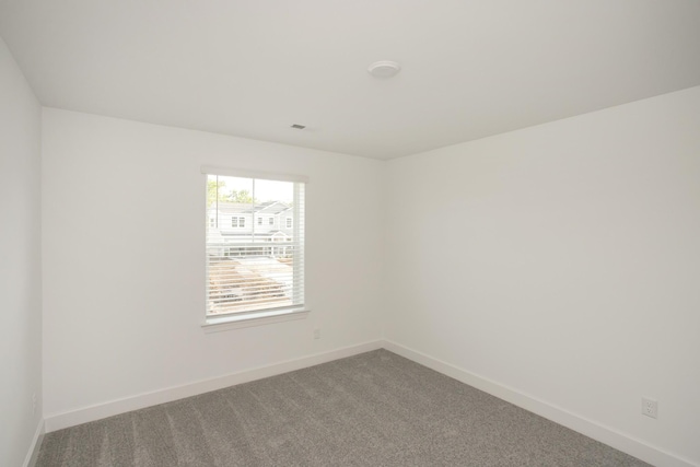 spare room featuring baseboards, visible vents, and carpet