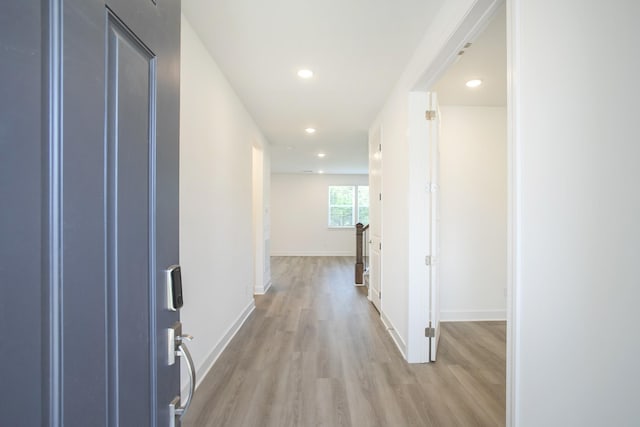 corridor featuring baseboards, light wood-style floors, and recessed lighting