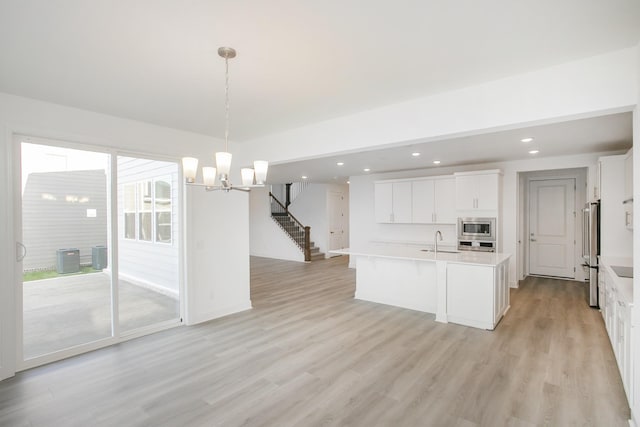 kitchen featuring a notable chandelier, appliances with stainless steel finishes, white cabinetry, light countertops, and light wood-type flooring